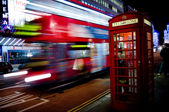 A London bus at night with its light ssmeared out into streaks