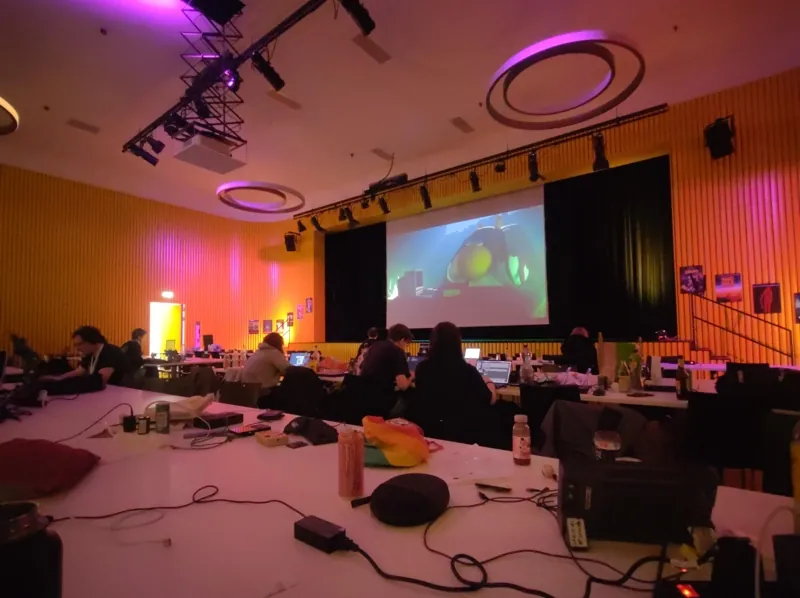 View of the projector screen across a table in the Dreiklang main hall.