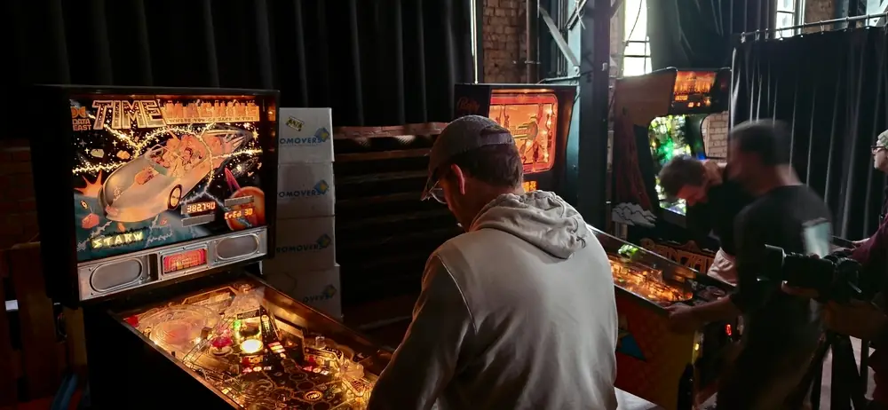 Some people playing pinball on restored machines.